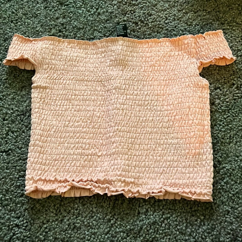 Off the shoulder light pink shirt.